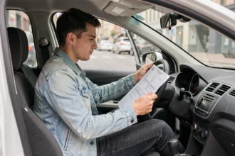 Jeune conducteur dans sa voiture consultant des documents d'assurance auto