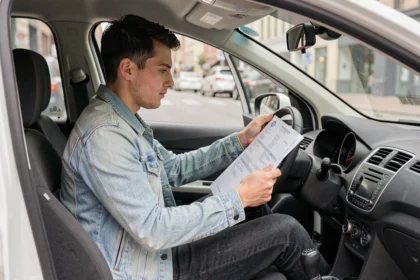 Jeune conducteur dans sa voiture consultant des documents d'assurance auto
