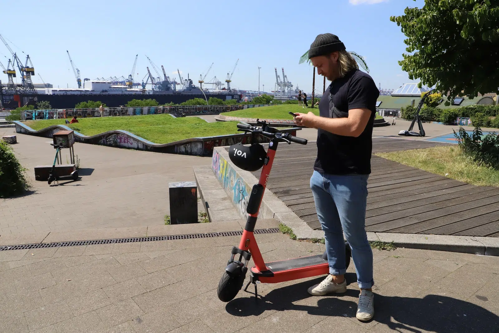 man in black t-shirt and blue denim jeans riding red and black kick scooter during