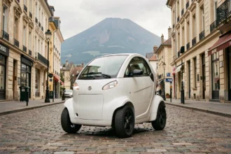 Voiture sans permis électrique garée dans une rue pavée de Clermont-Ferrand avec le Puy-de-Dôme en arrière-plan